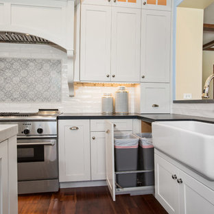 Bild på ett stort vintage grå grått kök, med en rustik diskho, skåp i shakerstil, vita skåp, bänkskiva i täljsten, vitt stänkskydd, stänkskydd i tunnelbanekakel, rostfria vitvaror, mörkt trägolv, en köksö och brunt golv