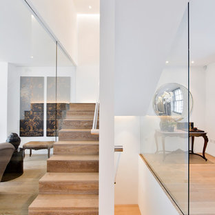 This is an example of a medium sized modern wood u-shaped glass railing staircase in London with wood risers.