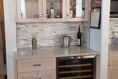 Trendy u-shaped dark wood floor home bar photo in Other with shaker cabinets, light wood cabinets, quartzite countertops, beige backsplash and mosaic tile backsplash