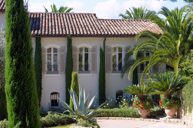 Cette photo montre une grande façade de maison blanche nature en béton à un étage avec un toit à deux pans et un toit en tuile.