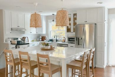 Eat-in kitchen - mid-sized transitional l-shaped medium tone wood floor and brown floor eat-in kitchen idea in DC Metro with a drop-in sink, recessed-panel cabinets, white cabinets, marble countertops, white backsplash, stainless steel appliances, an island and white countertops