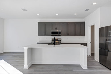 Example of a trendy kitchen design in Orlando with gray cabinets, an island and white countertops