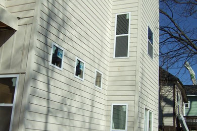 Diseño de fachada de casa moderna de tres plantas con revestimiento de aglomerado de cemento y tejado plano