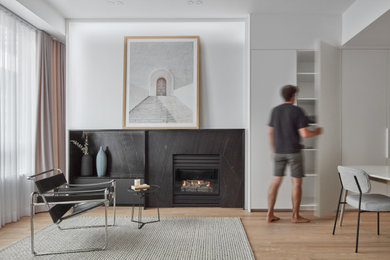 Diseño de salón para visitas abierto nórdico con suelo de madera en tonos medios, marco de chimenea de piedra y televisor independiente