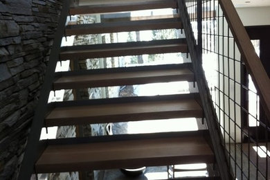Large trendy wooden u-shaped open and metal railing staircase photo in Other
