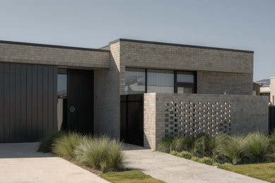 Inspiration for a large modern one-storey brick grey house exterior in Adelaide with a flat roof, a metal roof and a grey roof.