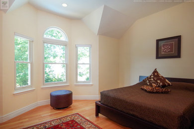 Example of a large master medium tone wood floor, multicolored floor and vaulted ceiling bedroom design in New York with yellow walls and no fireplace