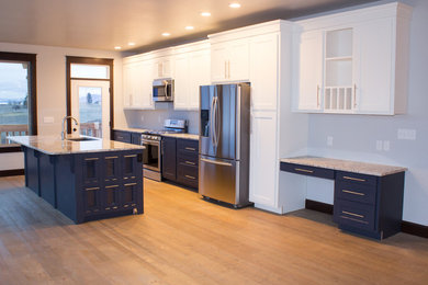 Example of a mid-sized transitional single-wall medium tone wood floor and brown floor eat-in kitchen design in Other with an undermount sink, shaker cabinets, white cabinets, granite countertops, stainless steel appliances and an island
