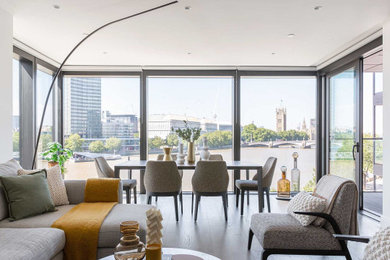 This is an example of a large contemporary formal and grey and black open plan living room in London with white walls, medium hardwood flooring, a freestanding tv, no fireplace, grey floors, a drop ceiling and feature lighting.