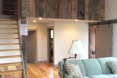 Inspiration for a mid-sized country loft-style family room in Manchester with white walls and medium hardwood floors.