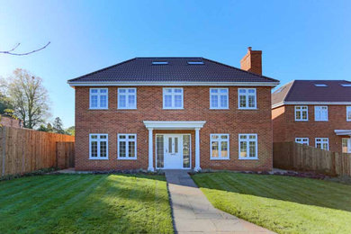 Photo of a large and red modern two floor brick detached house in Surrey with a tiled roof and a red roof.