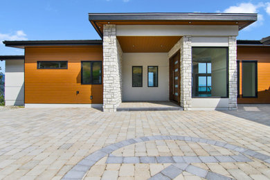 Example of a large minimalist gray one-story stucco house exterior design in Other with a butterfly roof, a shingle roof and a black roof