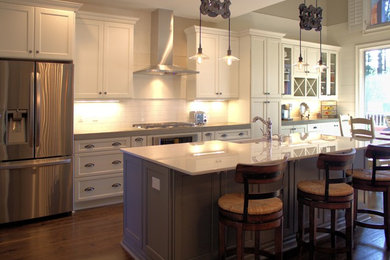 Inspiration for a large transitional single-wall medium tone wood floor and brown floor eat-in kitchen remodel in Atlanta with shaker cabinets, white cabinets, white backsplash, subway tile backsplash, stainless steel appliances, an island, an undermount sink and quartz countertops