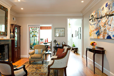 Elegant enclosed medium tone wood floor living room photo in DC Metro with beige walls, a standard fireplace and no tv