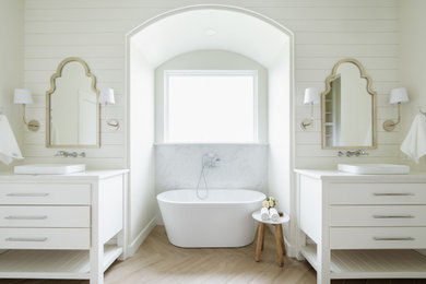 Design ideas for a transitional bathroom in Oklahoma City with flat-panel cabinets, white cabinets, a freestanding tub, white walls, light hardwood floors, a drop-in sink, beige floor, white benchtops, a double vanity, a freestanding vanity and planked wall panelling.