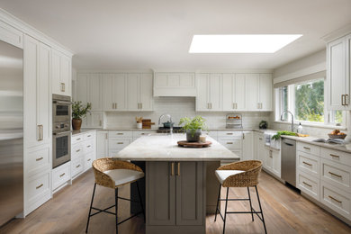 Inspiration for a mid-sized contemporary u-shaped medium tone wood floor and brown floor enclosed kitchen remodel in Seattle with a farmhouse sink, shaker cabinets, white cabinets, white backsplash, subway tile backsplash, stainless steel appliances, an island, gray countertops and granite countertops