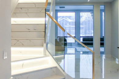 Foto de escalera en L actual de tamaño medio con escalones de mármol, contrahuellas de mármol y barandilla de metal
