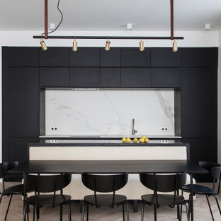 Cette image montre une cuisine américaine parallèle design avec un placard à porte plane, des portes de placard noires, une crédence blanche, un îlot central, un sol gris et un plan de travail blanc.