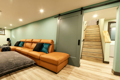 Large traditional fully buried basement in Edmonton with a home cinema, green walls, vinyl flooring and grey floors.