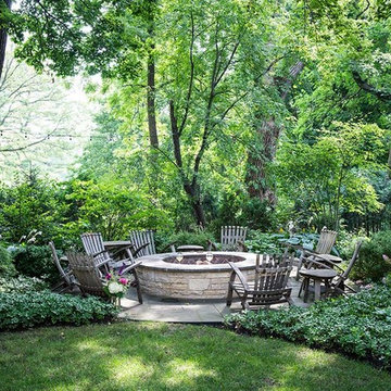 Large fire pit set into woodland with lush plantings