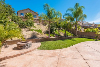 Photo of a large mediterranean full sun backyard concrete paver landscaping in San Diego with a fire pit.