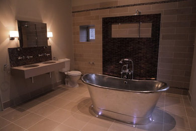Foto de cuarto de baño tradicional grande con bañera exenta, ducha abierta, sanitario de dos piezas, baldosas y/o azulejos en mosaico, paredes beige, suelo de piedra caliza y lavabo suspendido