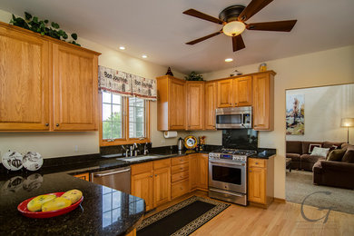 Inspiration for a large timeless galley light wood floor eat-in kitchen remodel in Chicago with an undermount sink, raised-panel cabinets, light wood cabinets, granite countertops, black backsplash, stone slab backsplash, stainless steel appliances and a peninsula