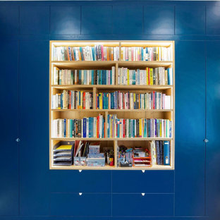 Photo of a large modern study in London with blue walls, laminate floors, a built-in desk and blue floors.