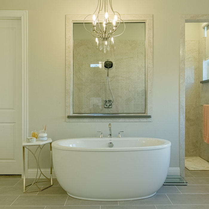 This beautiful free standing tub was enhanced by using a simple yet elegant chandelier. Coastal-inspired art completes the room.