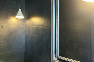 Powder room - small industrial black tile medium tone wood floor, brown floor and wall paneling powder room idea in Hamilton with a one-piece toilet, black walls, a vessel sink, gray countertops and a floating vanity