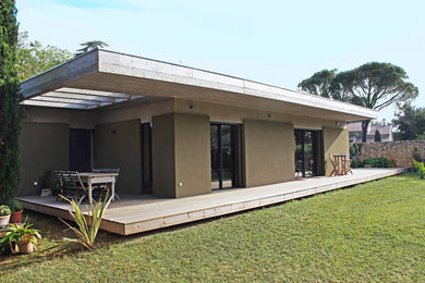 Idées déco pour une grande façade de maison beige contemporaine en béton de plain-pied avec un toit plat et un toit végétal.