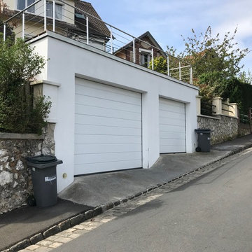 Création d'un double garage dans une rue pentue, avec une terrasse accessible.