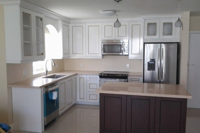 Mid-sized elegant l-shaped beige floor open concept kitchen photo in Miami with an undermount sink, shaker cabinets, white cabinets, beige backsplash, stone slab backsplash, stainless steel appliances and an island