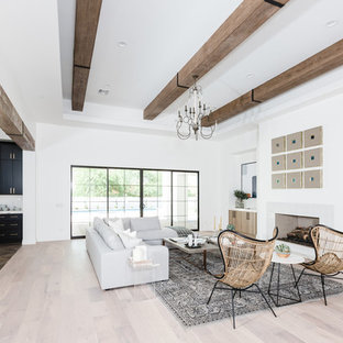 Foto de salón para visitas abierto, mediterráneo, grande, con paredes blancas, suelo de madera clara, chimenea tradicional y marco de chimenea de baldosas y/o azulejos