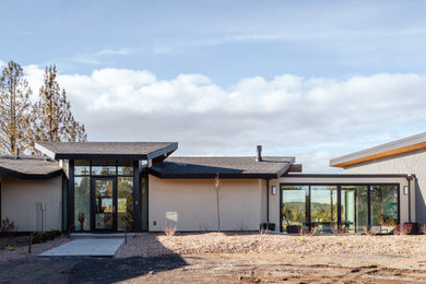 Diseño de fachada de casa beige y negra retro a niveles con revestimiento de estuco, tejado a dos aguas y tejado de teja de madera