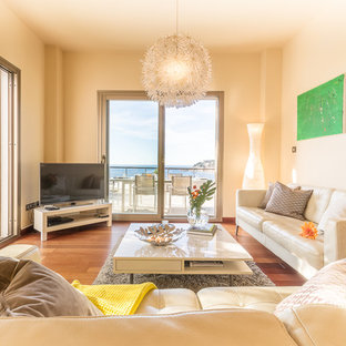 Foto de salón abierto, mediterráneo, de tamaño medio, con paredes beige, suelo laminado, televisor independiente y suelo marrón