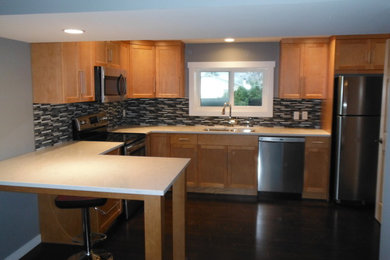 Example of a trendy u-shaped eat-in kitchen design in Vancouver with an undermount sink, shaker cabinets, light wood cabinets, granite countertops, multicolored backsplash, glass tile backsplash and stainless steel appliances