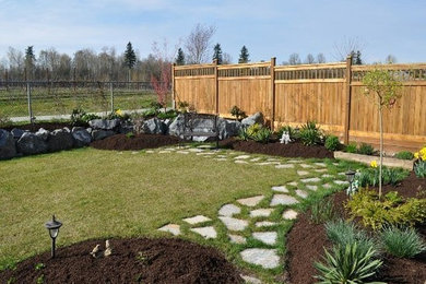 This is an example of a large traditional full sun backyard stone landscaping in Edmonton.