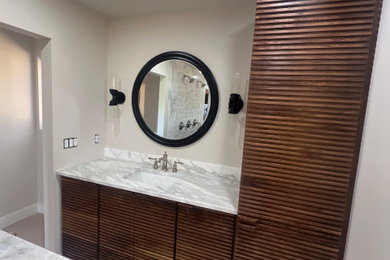 Bathroom - large eclectic master white tile and marble tile marble floor, white floor and double-sink bathroom idea with furniture-like cabinets, brown cabinets, a two-piece toilet, beige walls, an undermount sink, marble countertops, a hinged shower door, white countertops, a niche and a built-in vanity