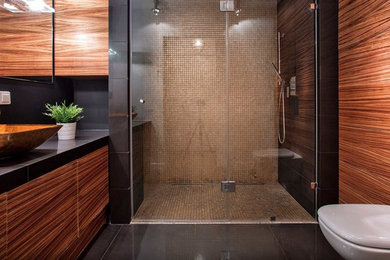 Inspiration for a mid-sized contemporary 3/4 brown tile and mosaic tile black floor alcove shower remodel in San Francisco with flat-panel cabinets, brown cabinets, a vessel sink, solid surface countertops, a hinged shower door and black countertops