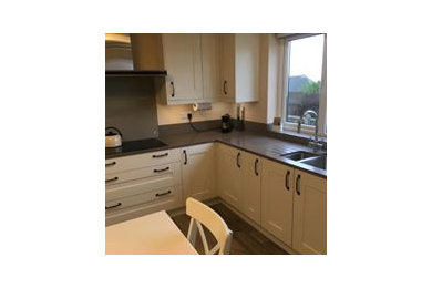 Photo of a large classic u-shaped kitchen/diner in Other with a built-in sink, shaker cabinets, beige cabinets, composite countertops, brown splashback, glass sheet splashback, stainless steel appliances, vinyl flooring, no island, brown floors and brown worktops.