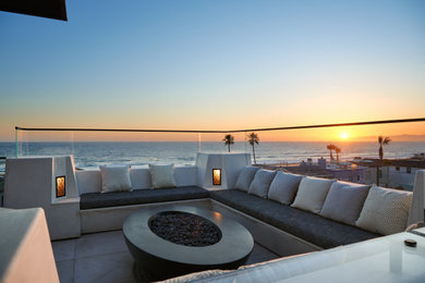 ロサンゼルスにあるラグジュアリーな広い地中海スタイルのおしゃれなベランダ・バルコニー (屋外暖炉、張り出し屋根、ガラスフェンス) の写真