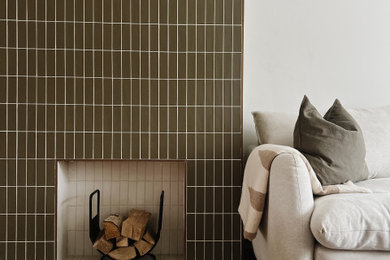 This is an example of a medium sized modern living room in London with white walls, medium hardwood flooring, a standard fireplace, a tiled fireplace surround, multi-coloured floors and a chimney breast.