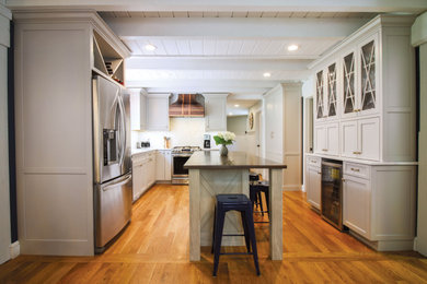 Inspiration for a mid-sized country l-shaped brown floor and medium tone wood floor kitchen remodel in Boston with a double-bowl sink, recessed-panel cabinets, gray cabinets, white backsplash, marble backsplash, stainless steel appliances, an island and brown countertops
