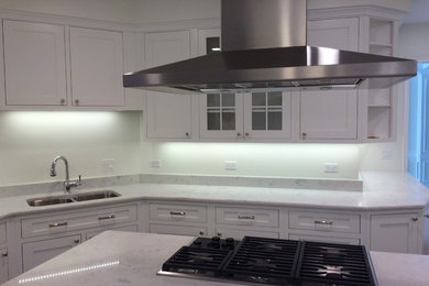Kitchen - large traditional porcelain tile kitchen idea in Chicago with shaker cabinets, white cabinets, quartz countertops, white backsplash, stone slab backsplash, stainless steel appliances and an island