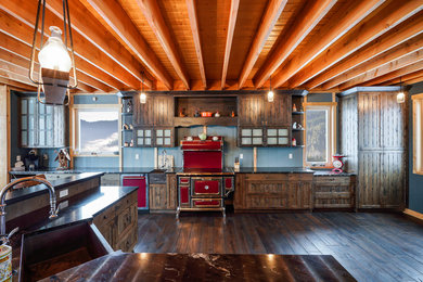 Eat-in kitchen - large rustic galley eat-in kitchen idea in Other with a farmhouse sink, recessed-panel cabinets, brown cabinets, quartzite countertops, colored appliances and an island