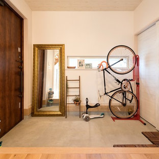 京都の片開きドアアジアンスタイルのおしゃれな玄関 (白い壁、コンクリートの床、濃色木目調のドア、グレーの床) の写真