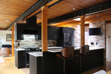 Inspiration for a mid-sized modern galley light wood floor and exposed beam eat-in kitchen remodel in Edmonton with an undermount sink, flat-panel cabinets, black cabinets, quartz countertops, brick backsplash, stainless steel appliances, a peninsula and white countertops