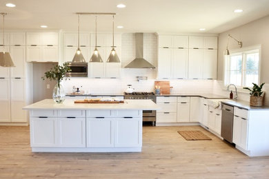 Example of a cottage vinyl floor kitchen design in Other with a farmhouse sink, shaker cabinets, white cabinets, quartz countertops, white backsplash, subway tile backsplash, stainless steel appliances, an island and gray countertops