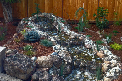 Design ideas for a rustic backyard concrete paver water fountain landscape in Sacramento.